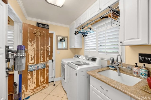 washroom featuring light tile patterned flooring, a sink, ornamental molding, cabinet space, and washer and clothes dryer