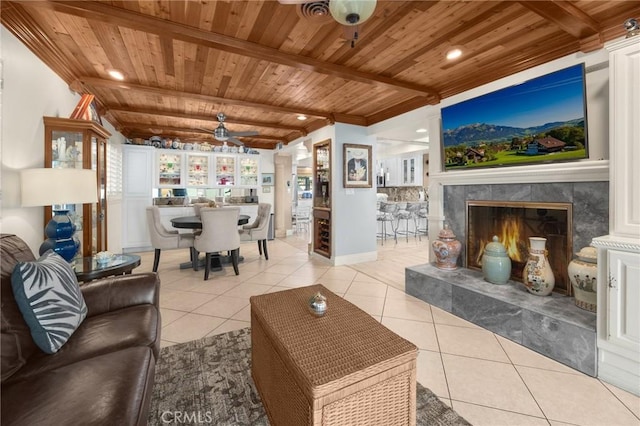 living room featuring a ceiling fan, wood ceiling, a premium fireplace, and light tile patterned floors