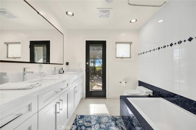 full bath featuring toilet, a sink, visible vents, tile patterned floors, and tiled tub