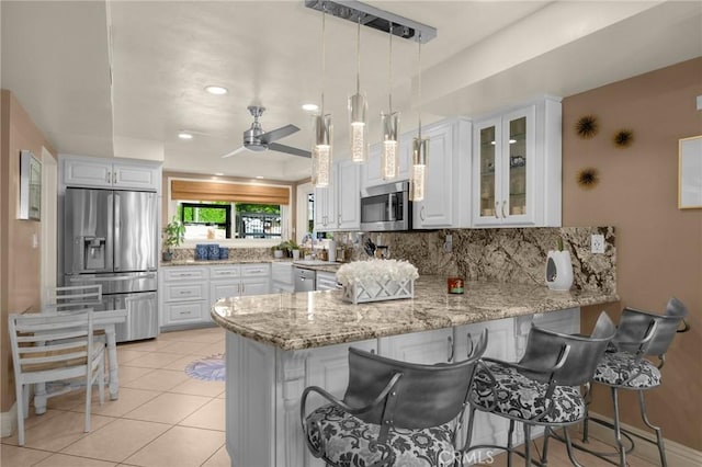 kitchen with stainless steel appliances, white cabinets, glass insert cabinets, and a peninsula