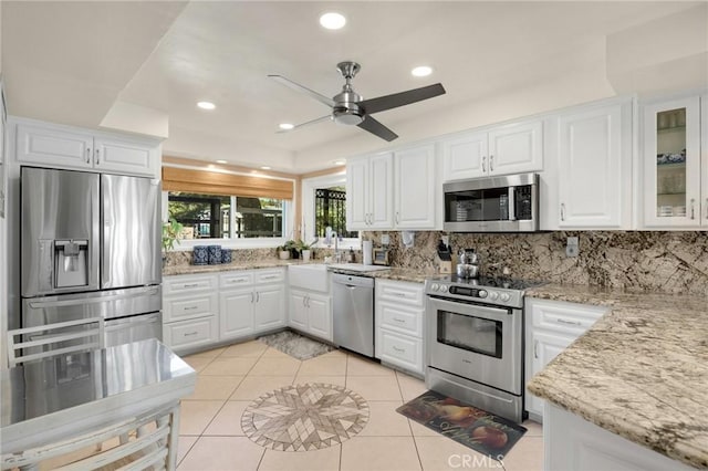 kitchen with light tile patterned flooring, white cabinetry, appliances with stainless steel finishes, tasteful backsplash, and glass insert cabinets