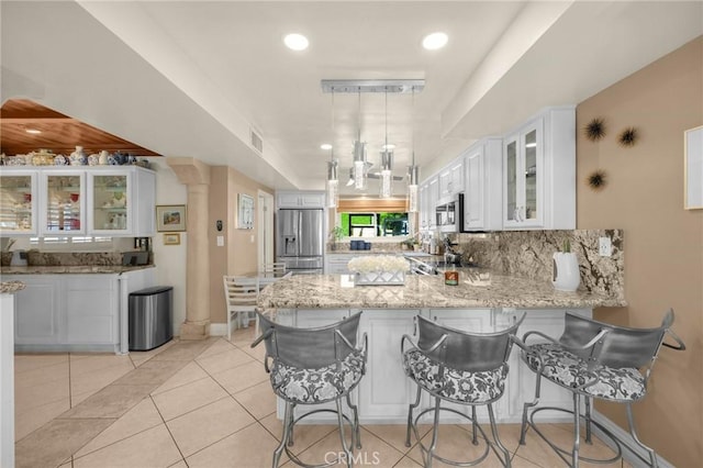 kitchen featuring decorative backsplash, appliances with stainless steel finishes, glass insert cabinets, a peninsula, and white cabinetry