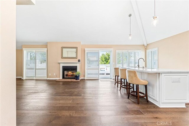 kitchen featuring a kitchen breakfast bar, a wealth of natural light, vaulted ceiling with beams, and hanging light fixtures