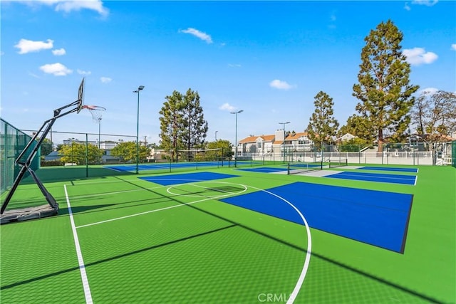 view of basketball court featuring a tennis court, community basketball court, and fence