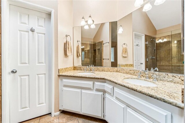 full bath featuring a stall shower, lofted ceiling, tile patterned flooring, and a sink