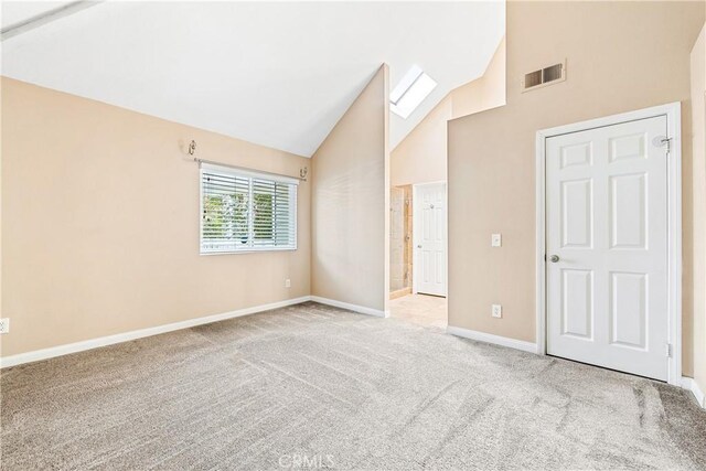 unfurnished room featuring high vaulted ceiling, visible vents, light carpet, and baseboards