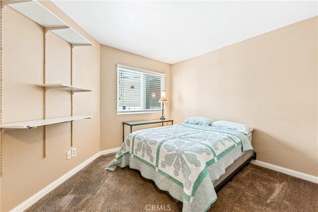 bedroom featuring baseboards and dark carpet