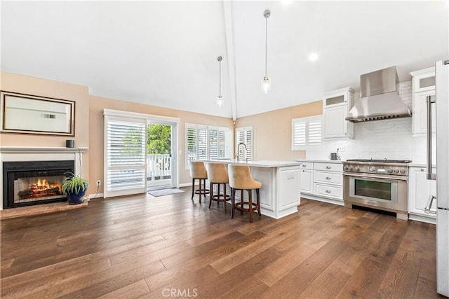 kitchen with white cabinetry, a center island with sink, wall chimney range hood, high end appliances, and pendant lighting