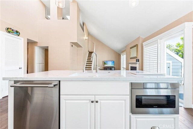 kitchen featuring dark wood-style flooring, appliances with stainless steel finishes, open floor plan, white cabinets, and a sink