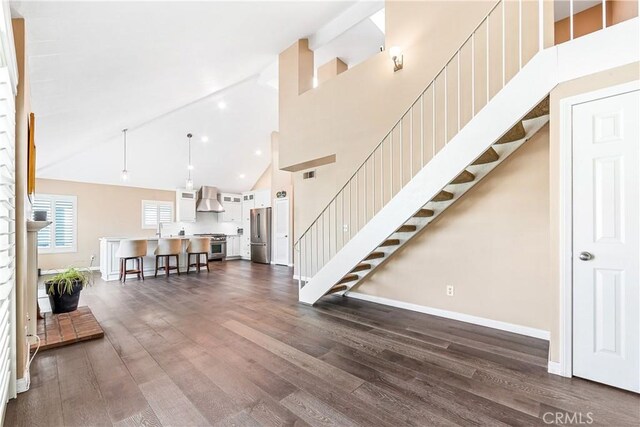 entryway featuring dark wood-style floors, high vaulted ceiling, and stairs