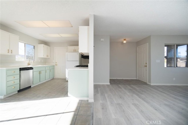 kitchen with a sink, baseboards, open floor plan, light countertops, and dishwasher