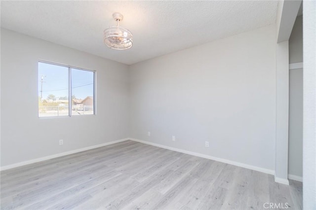6213 Baileya Ave Unit 29, Palms, CA 92277 - spare room featuring light wood finished floors, baseboards, an inviting chandelier, and a textured ceiling