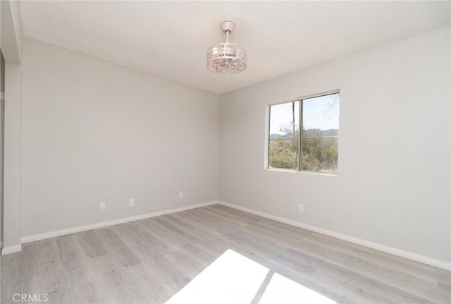 spare room with a textured ceiling and light hardwood / wood-style flooring