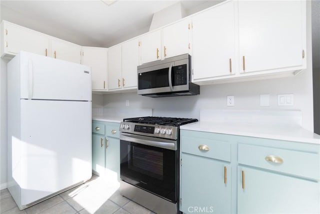 kitchen featuring light tile patterned floors, blue cabinets, stainless steel appliances, and white cabinetry