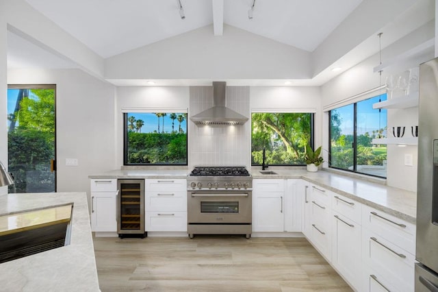 kitchen with white cabinetry, stainless steel range, beverage cooler, wall chimney range hood, and light stone counters