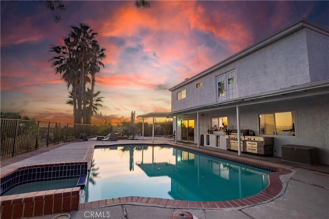 pool at dusk featuring an in ground hot tub, a patio, and area for grilling