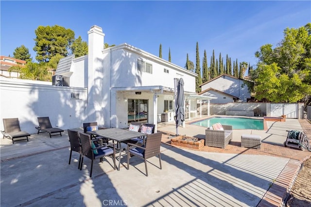 back of property with a fenced in pool and a patio