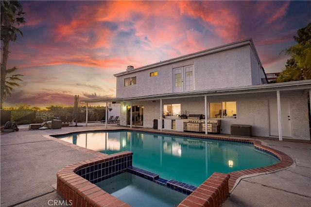 pool at dusk featuring an in ground hot tub, a patio area, and area for grilling