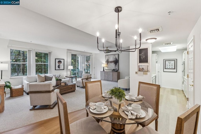 dining area featuring light wood-type flooring, a notable chandelier, and a wealth of natural light