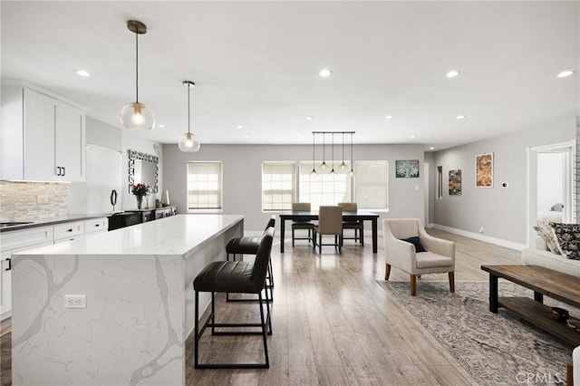 kitchen with pendant lighting, white cabinets, tasteful backsplash, and a center island