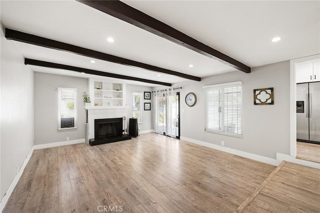 unfurnished living room with beamed ceiling and light hardwood / wood-style flooring