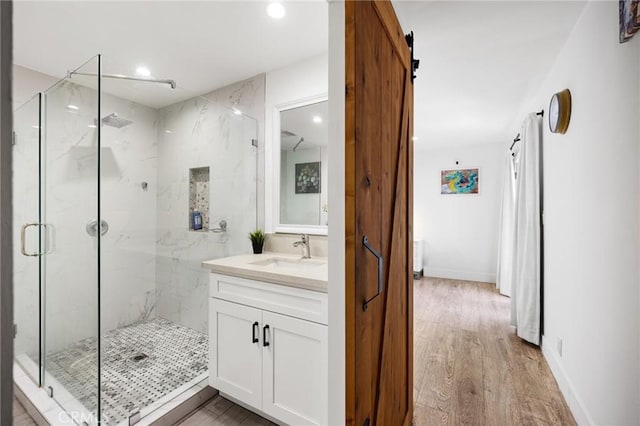 bathroom with hardwood / wood-style flooring, walk in shower, and vanity