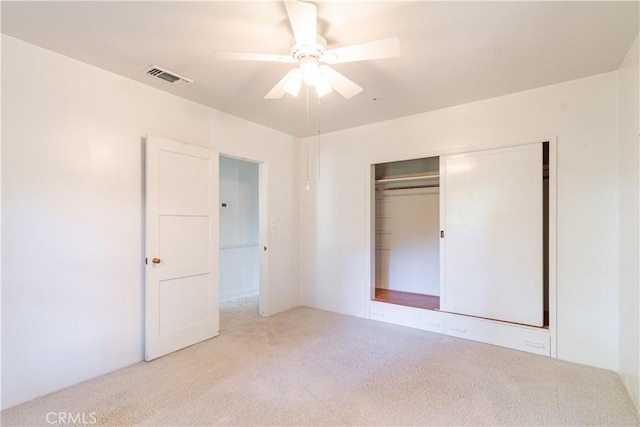 unfurnished bedroom with ceiling fan, light carpet, and a closet