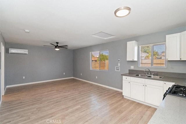 kitchen featuring an AC wall unit, sink, white cabinetry, and a healthy amount of sunlight