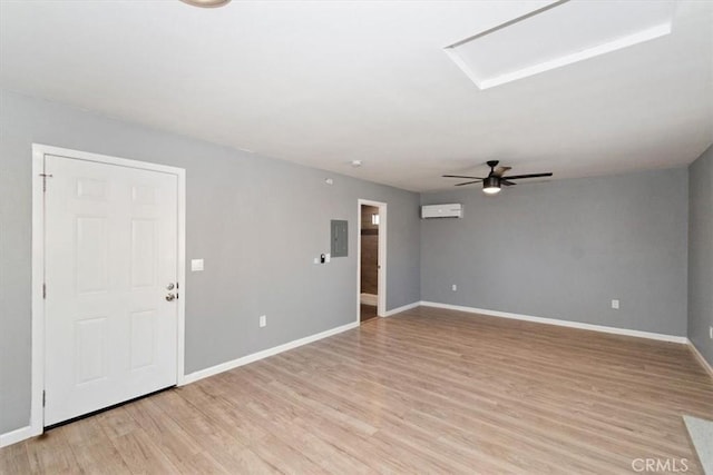 empty room with ceiling fan, light wood-type flooring, electric panel, and a wall mounted air conditioner