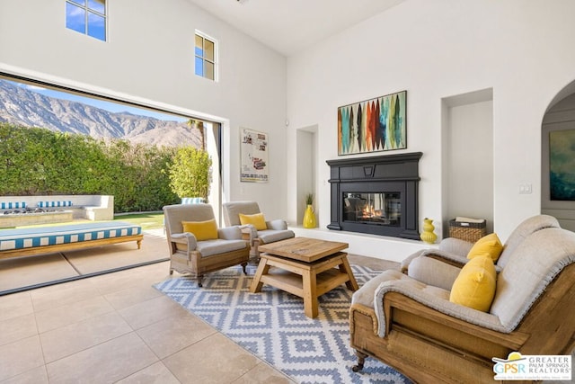 living room featuring a towering ceiling, tile patterned floors, and a mountain view