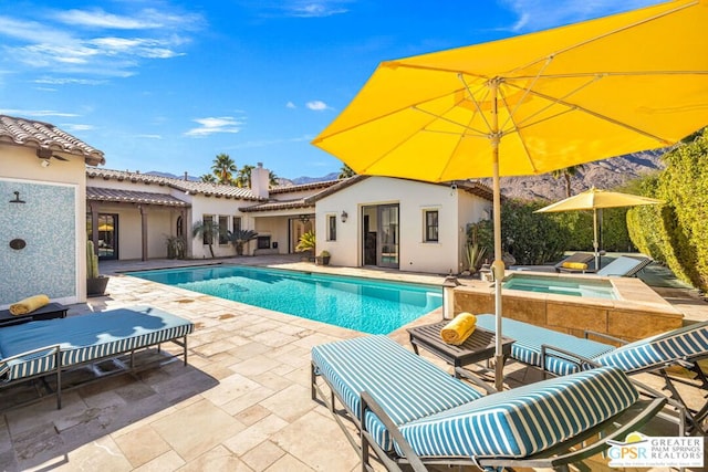 view of pool featuring an outbuilding, an in ground hot tub, and a patio