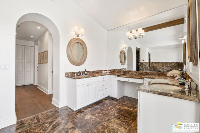 bathroom featuring vanity, lofted ceiling, and a chandelier