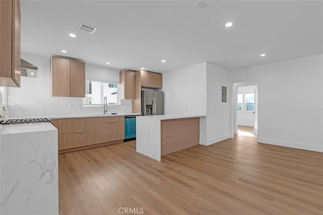 kitchen with light hardwood / wood-style floors, sink, stainless steel appliances, and a healthy amount of sunlight