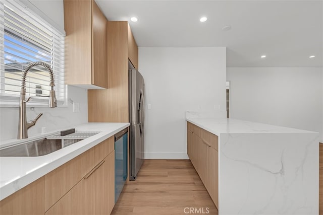 kitchen featuring sink, light hardwood / wood-style flooring, appliances with stainless steel finishes, and light brown cabinetry