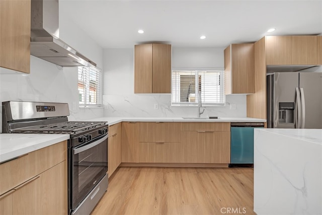 kitchen featuring wall chimney exhaust hood, plenty of natural light, light brown cabinetry, and appliances with stainless steel finishes