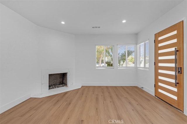 unfurnished living room featuring light hardwood / wood-style flooring and a fireplace