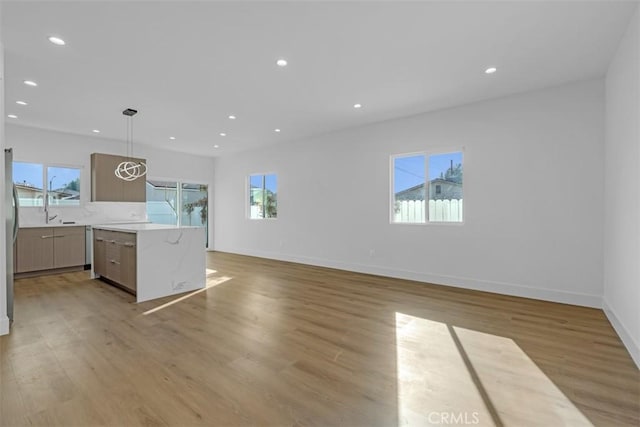 kitchen featuring pendant lighting, a center island, a healthy amount of sunlight, and light wood-type flooring