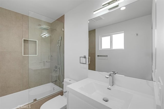 full bathroom with bath / shower combo with glass door, toilet, and vanity