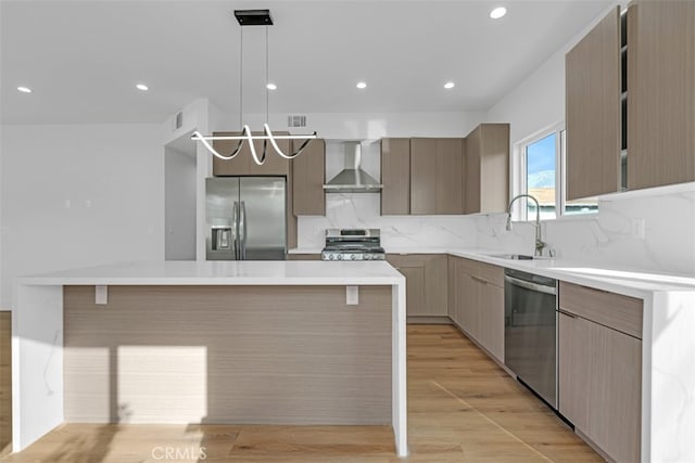 kitchen with stainless steel appliances, a center island, hanging light fixtures, and wall chimney exhaust hood