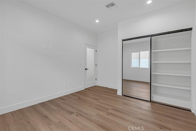 unfurnished bedroom featuring light hardwood / wood-style flooring and a closet