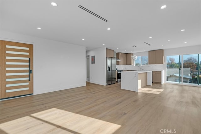 kitchen featuring light hardwood / wood-style floors, decorative backsplash, a kitchen island, pendant lighting, and stainless steel appliances