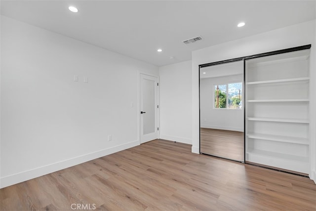 unfurnished bedroom featuring light hardwood / wood-style flooring and a closet