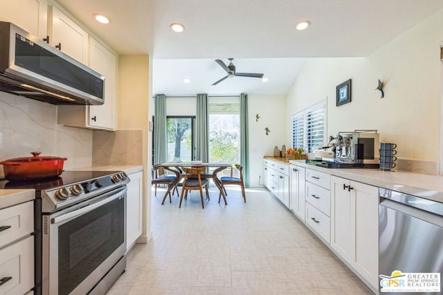 kitchen featuring appliances with stainless steel finishes, lofted ceiling, white cabinetry, backsplash, and ceiling fan