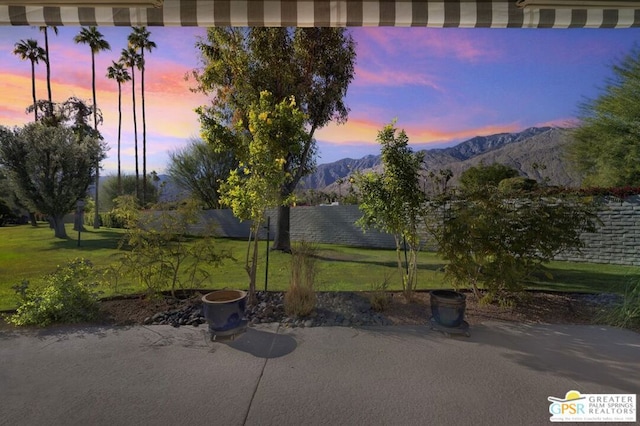 patio terrace at dusk featuring a lawn and a mountain view