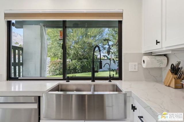 kitchen with backsplash, dishwasher, sink, white cabinetry, and light stone countertops