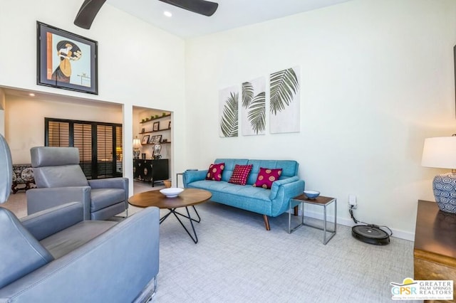 carpeted living room featuring ceiling fan and a high ceiling