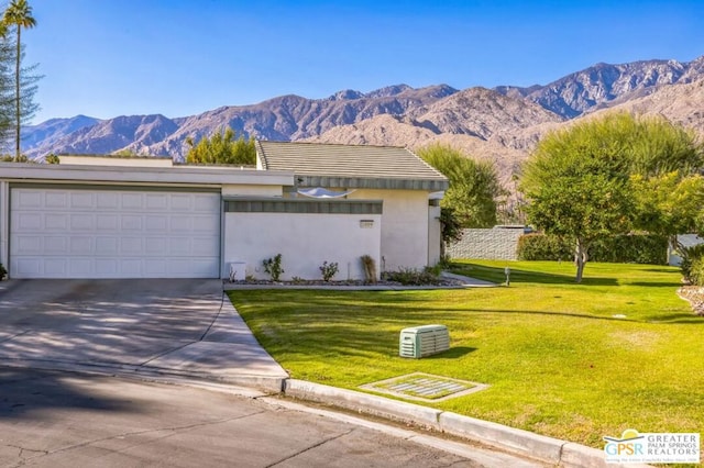 view of front facade with a mountain view, a front lawn, and a garage