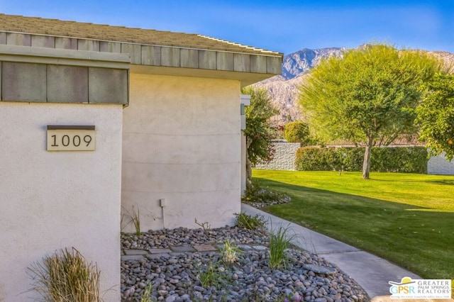 view of property exterior with a mountain view and a lawn