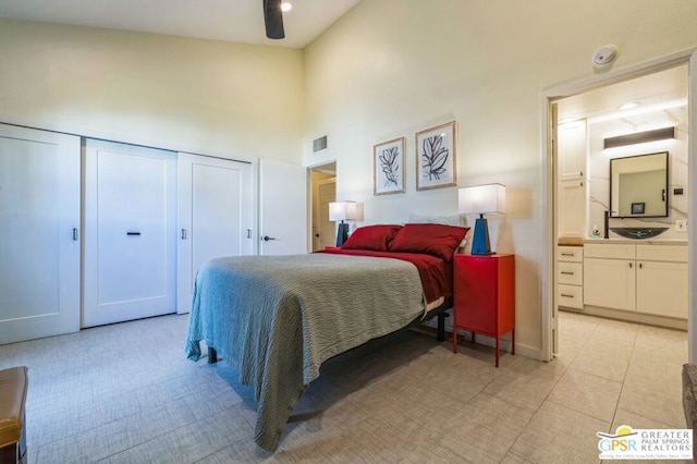 bedroom with ceiling fan, ensuite bath, and a towering ceiling