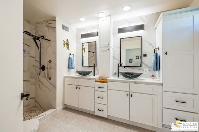 bathroom with toilet, vanity, and a tile shower